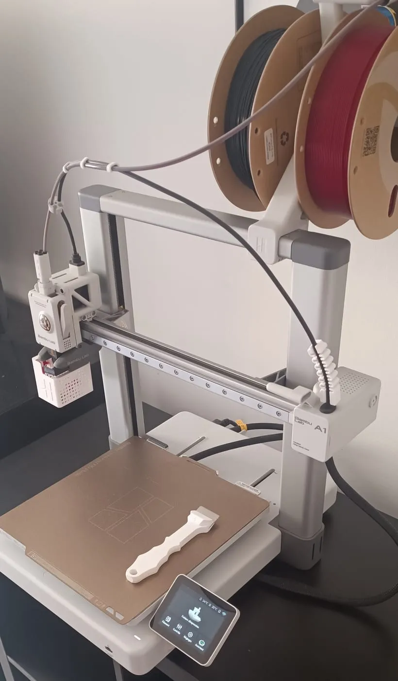 Ma Bambu Lab A1 installée sur un meuble, avec deux bobines de PLA eSun sur un support imprimé et un grattoir imprimé posé sur le plateau