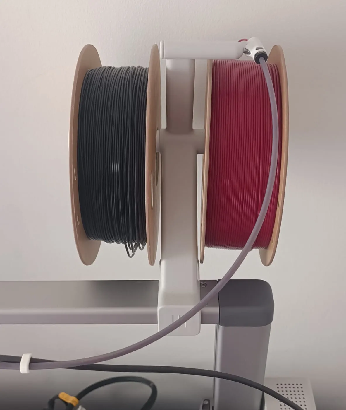 Support imprimé qui tient deux bobines de PLA eSun, noire et rouge, au-dessus de la Bambu Lab A1
