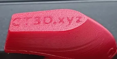 Dessous d'un bateau 3DBenchy en PLA rouge, avec l'inscription CT3D.xyz en relief, imprimé sur une plaque Textured PEI